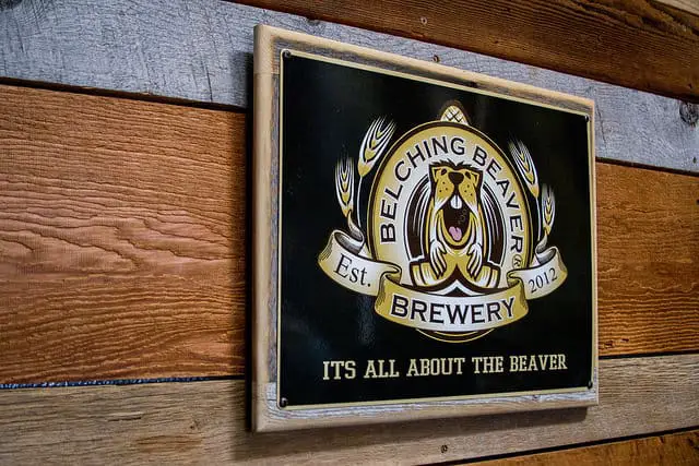 Frame with Belching Beaver Brewery Logo with Motto Mounted on a Wooden Wall at the Dining Area