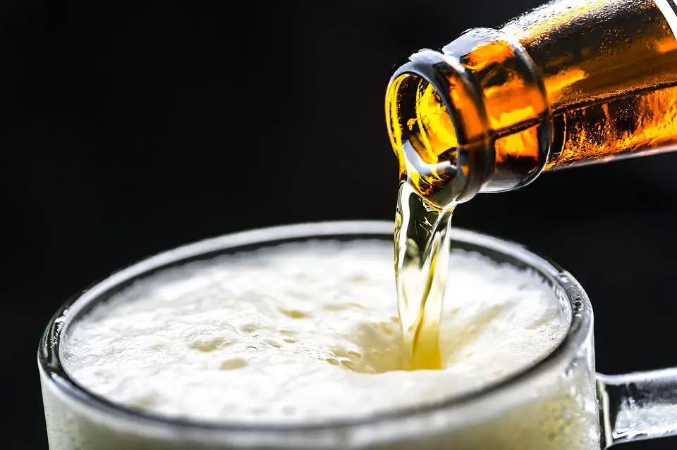 Chilled Craft Beer Beverage Being Poured from the Bottle on a Glass Nearly-Filled