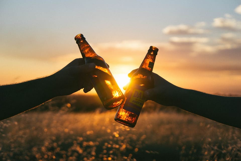 making a toast with beer bottles 