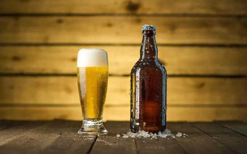 A glass of beer beside a bottle
