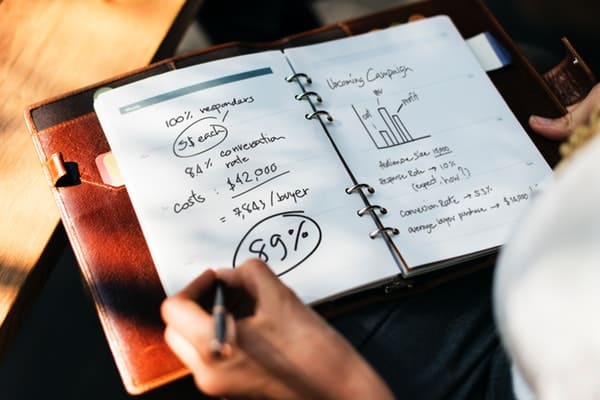 person writing business plan in notebook