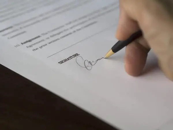 man writing a signature on a paper